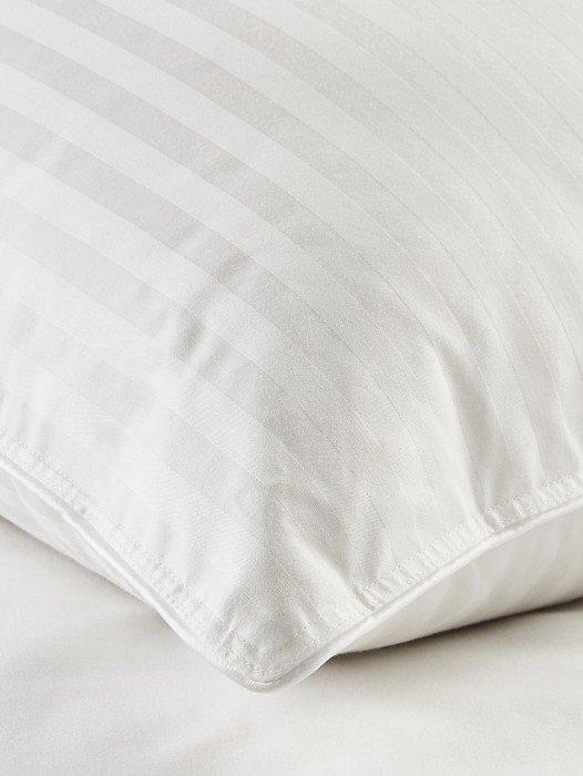 a close up of a pillow on a bed with a white cover