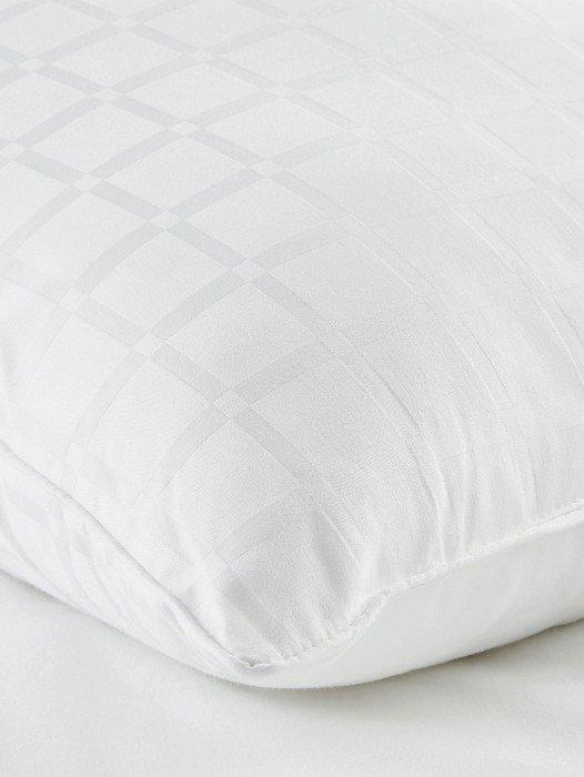 a close up of a pillow on a bed with a white cover