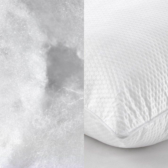 a white pillow next to a white bed with a white comforter