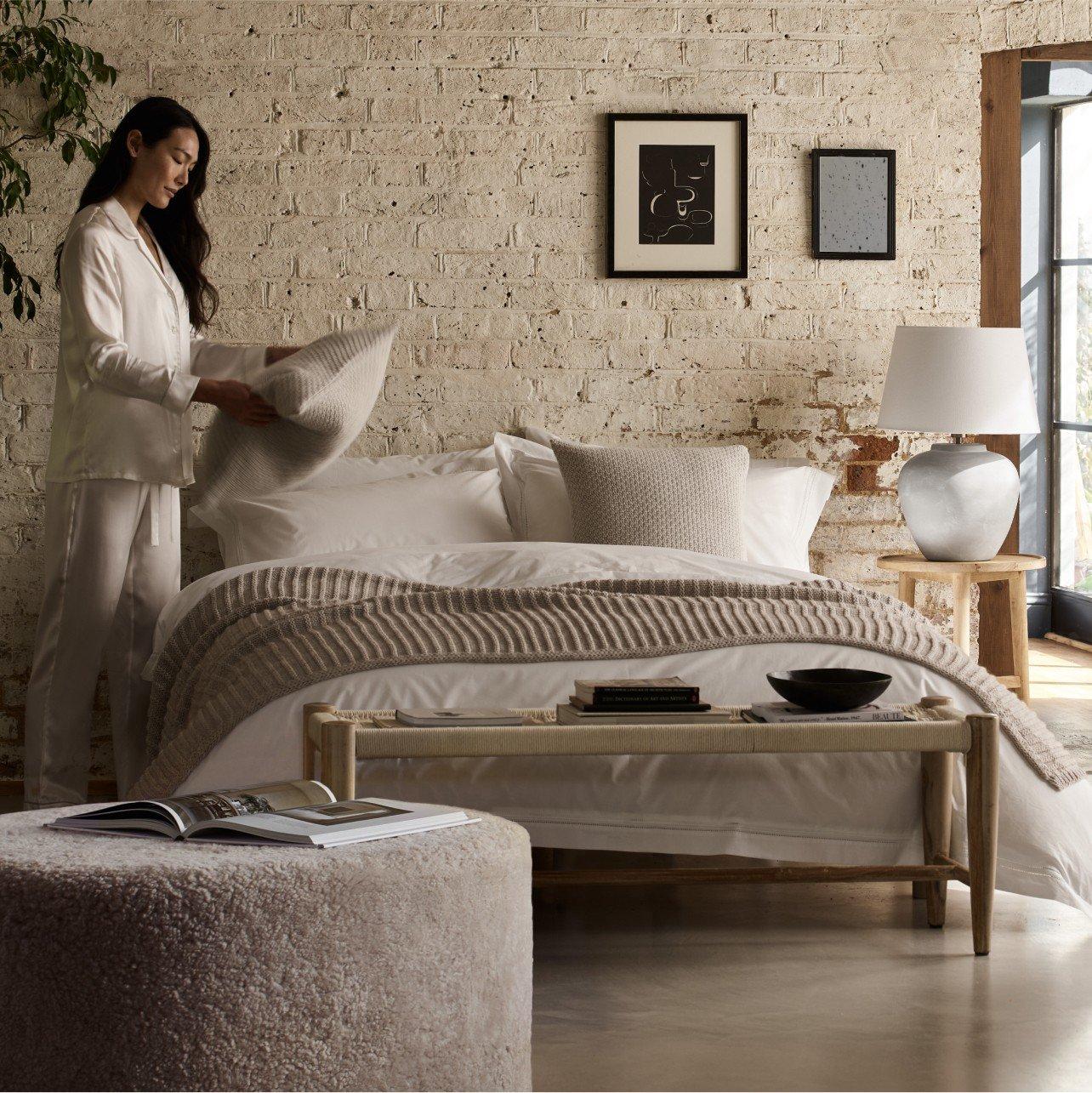 a woman in a white pajama standing in front of a bed