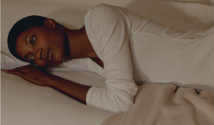 a woman laying on a bed with a white shirt on