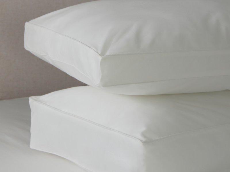 a stack of pillows on a bed with a white sheet