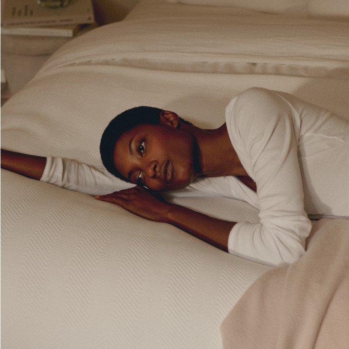 a woman laying on a bed with a white sheet