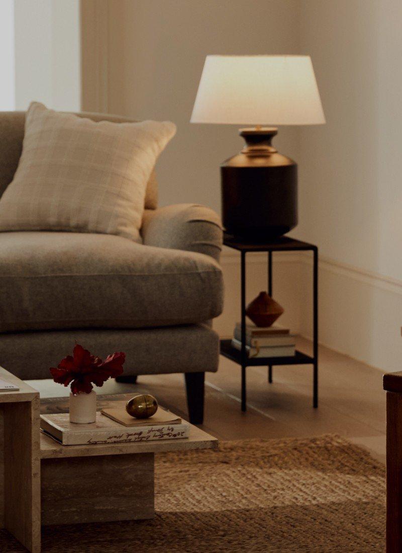 a woman standing in a living room with a lamp on