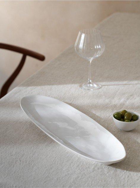 a white plate with a bowl of olives and a glass of wine