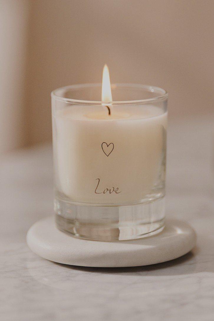 a small candle with a heart on it sitting on a marble table