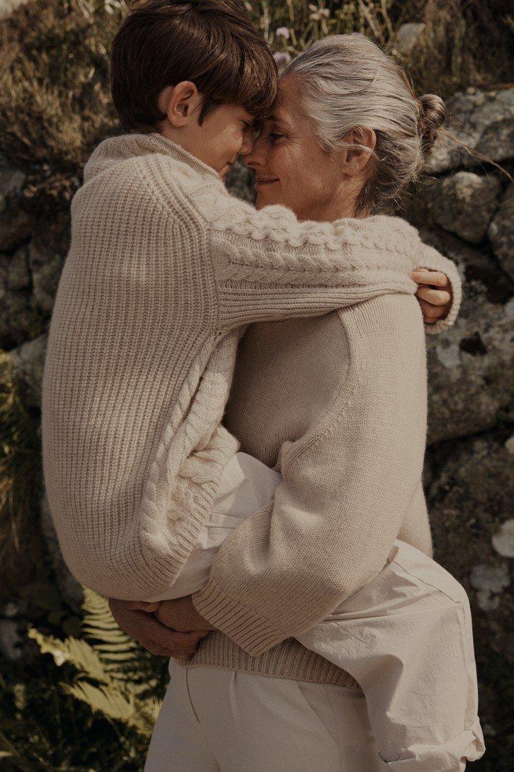 a woman and boy hugging each other in a field