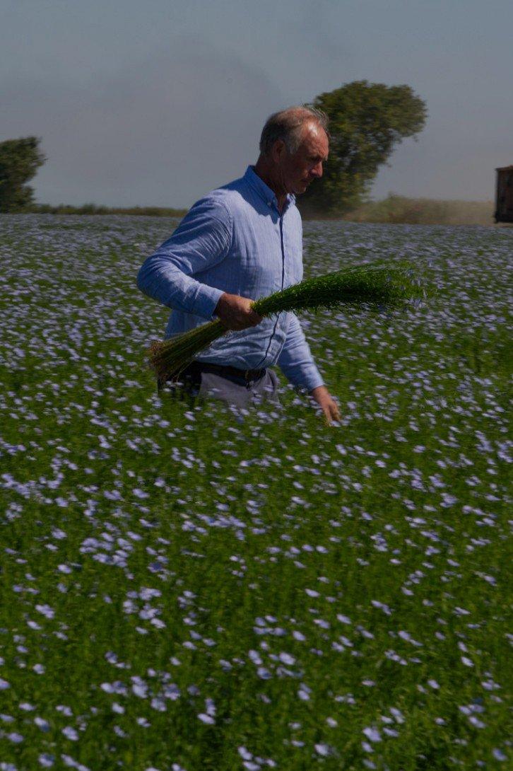 a man walking through a field of tall grass with a bundle of grass