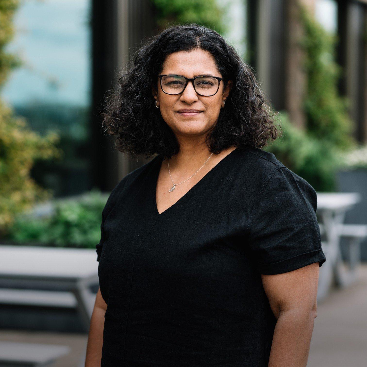 a woman with glasses and curly hair standing outside