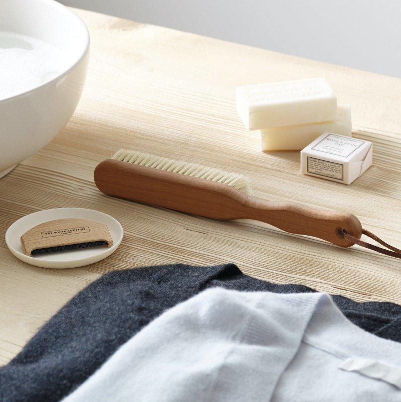 a wooden table with a bottle of shampoo, a brush, a bottle of soap, and a