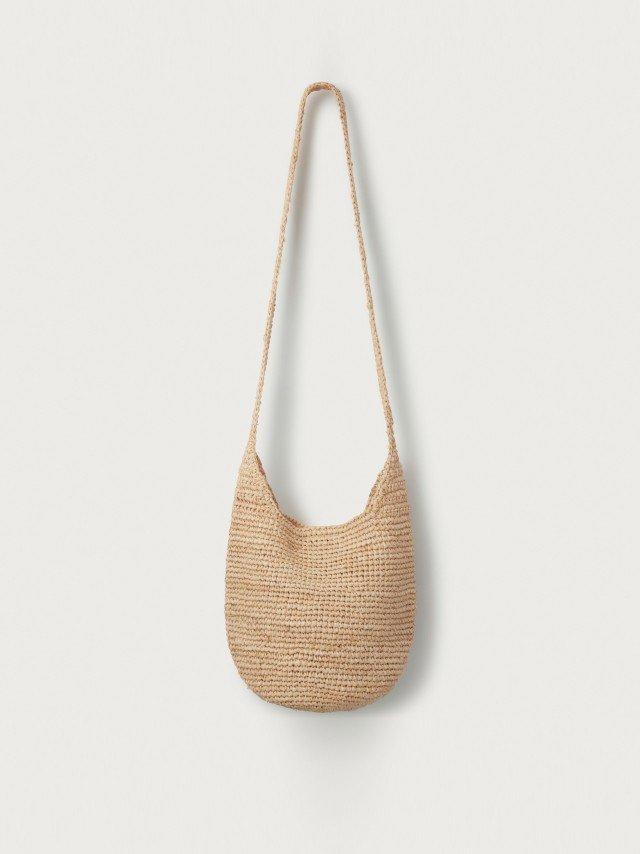 the woven bag is hanging on a white wall