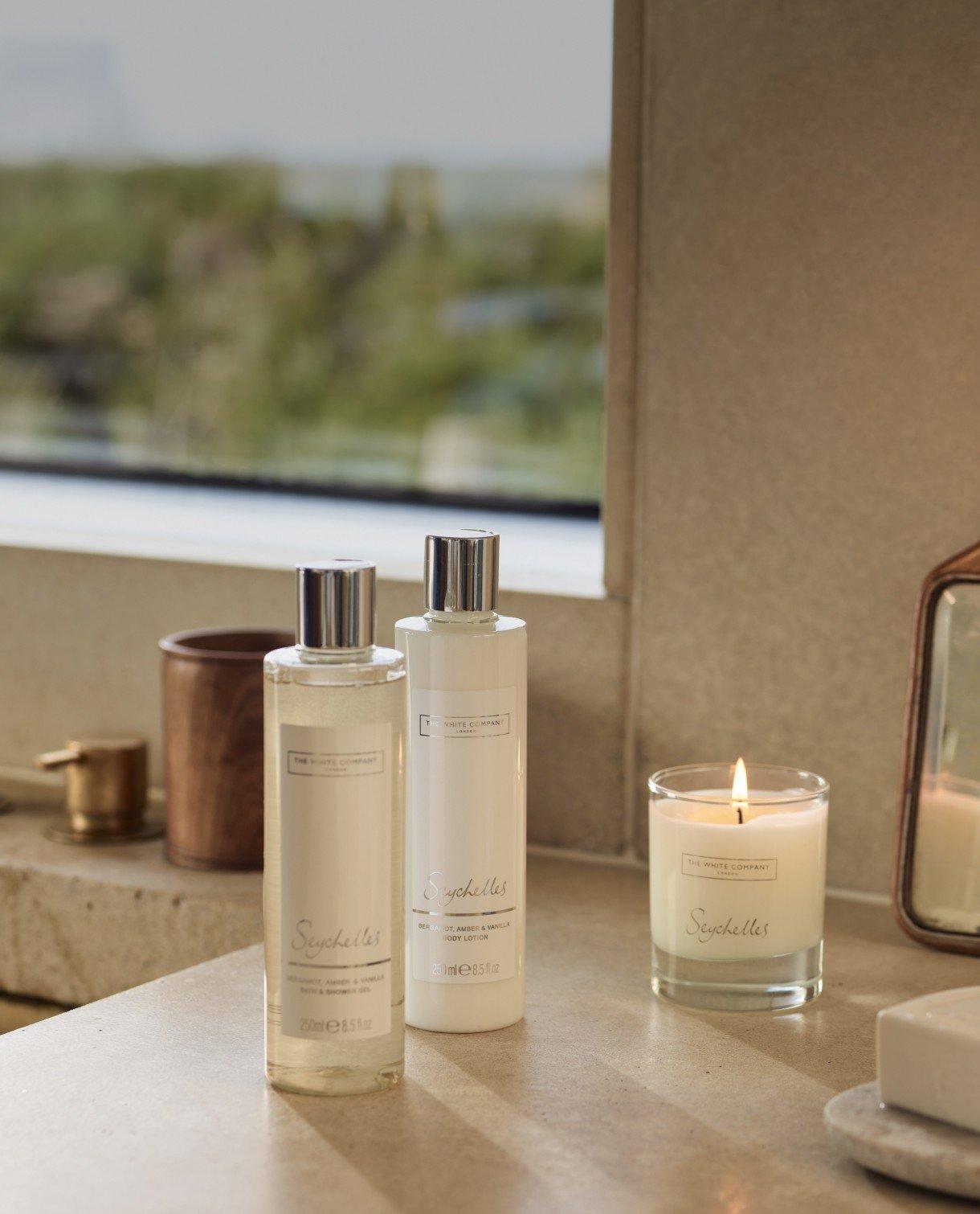 a bathroom counter with two bottles of lotion and a candle