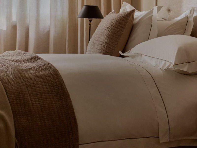 a bed with a white comforter and pillows in a room