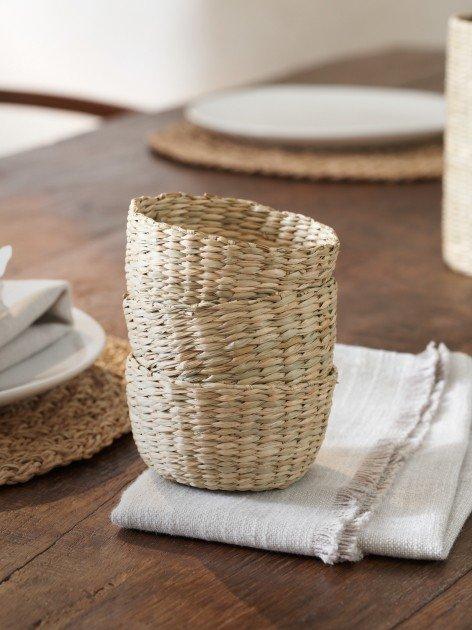 a stack of woven baskets on a wooden table with napkins