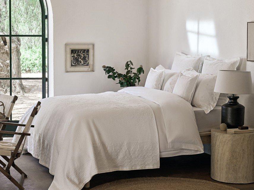 a bedroom with a white bed and a large window