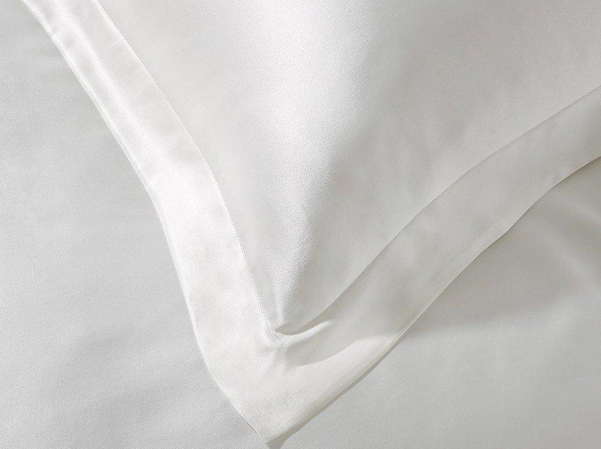 a close up of a white bed with a white pillow