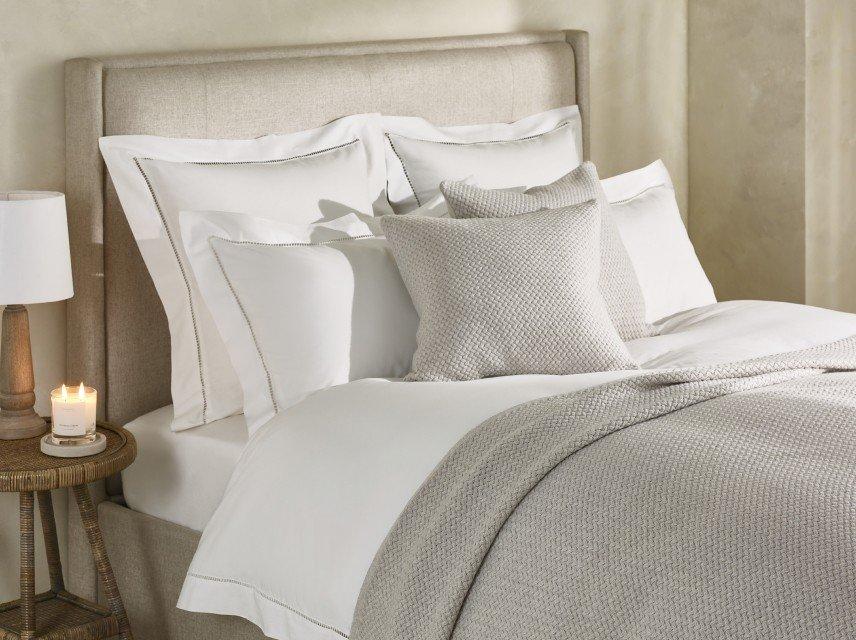a bed with a white comforter and pillows on it