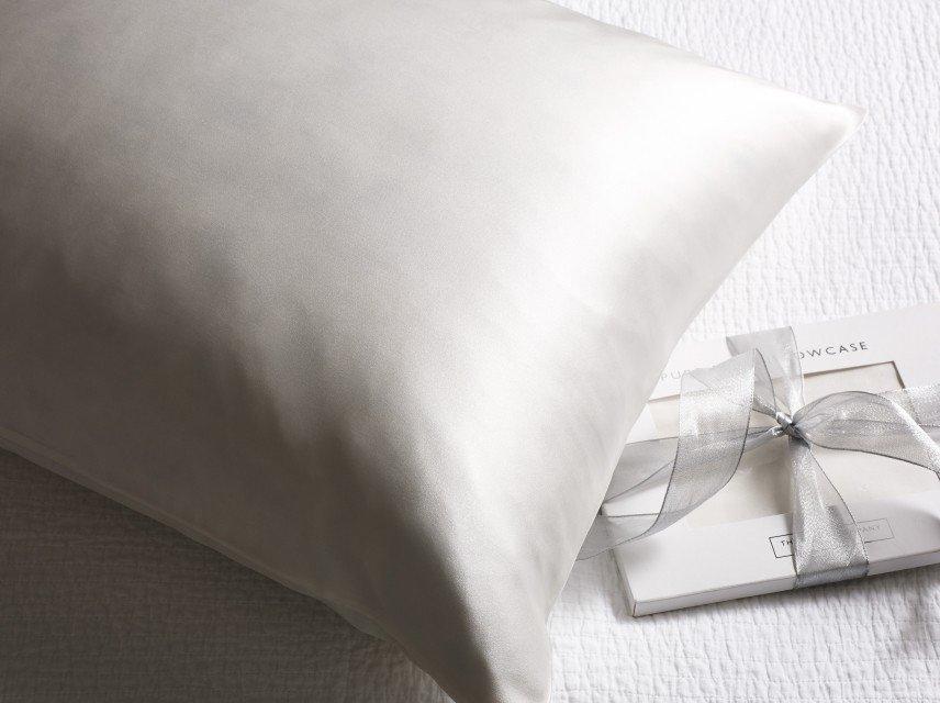 a white pillow with a ribbon tied around it sitting on a bed
