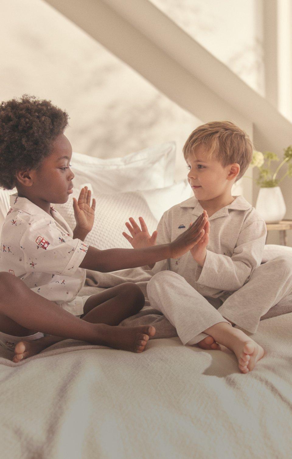 two children are sitting next to each other on a bed