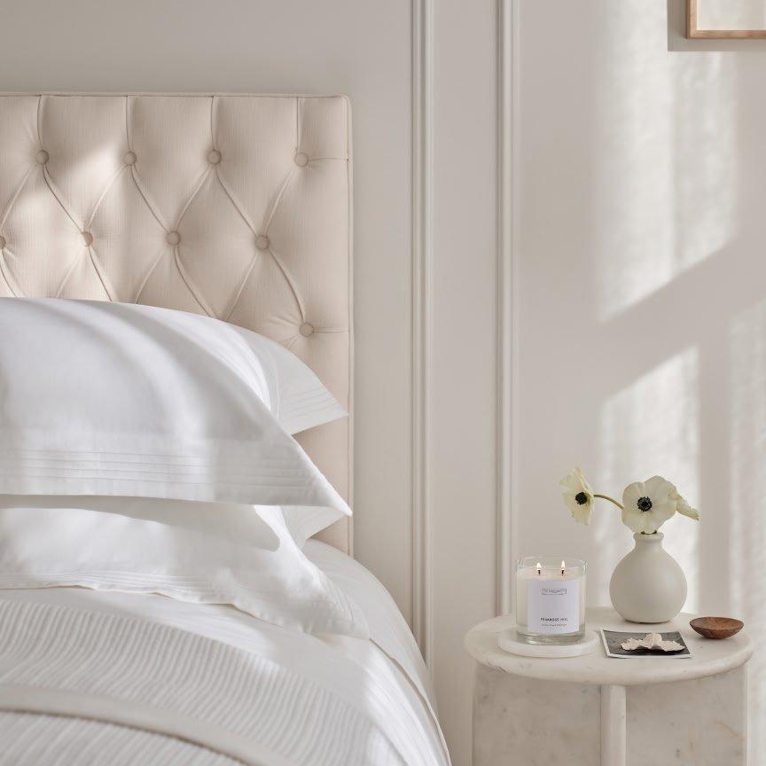 a bed with a white comforter and pillows in a bedroom
