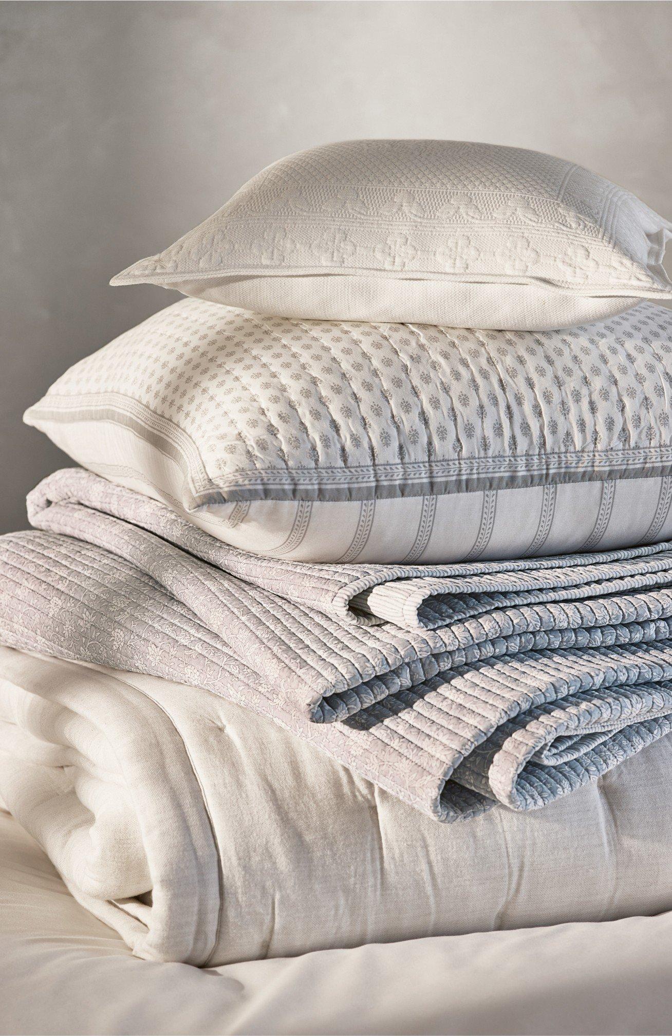 a stack of pillows on a bed with a white sheet