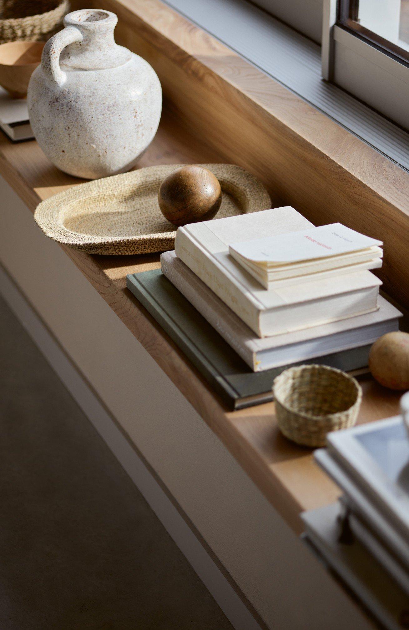 a window sill with a vase, bowls, and books on it