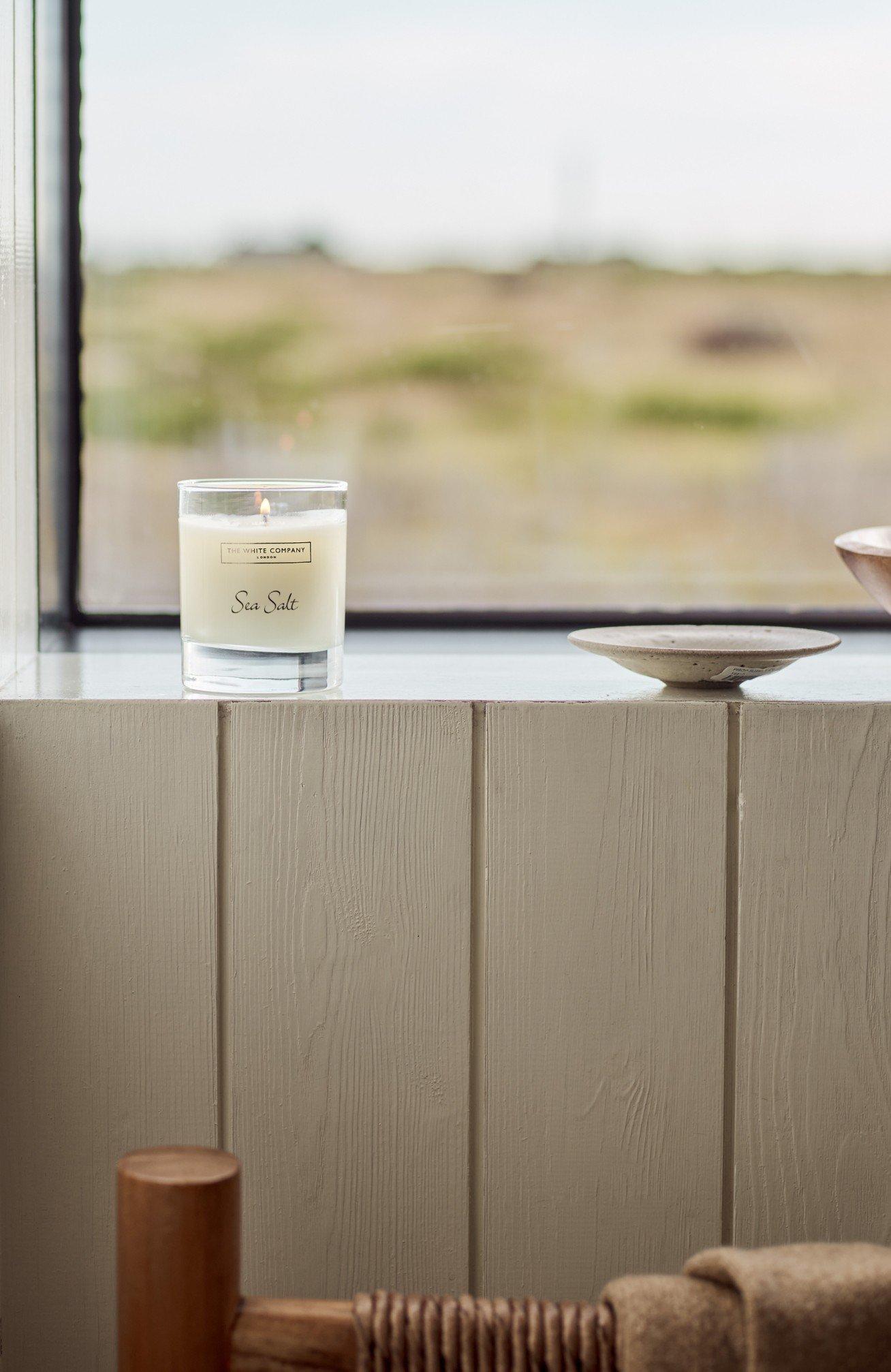 a candle and a bowl on a window sill in a bathroom