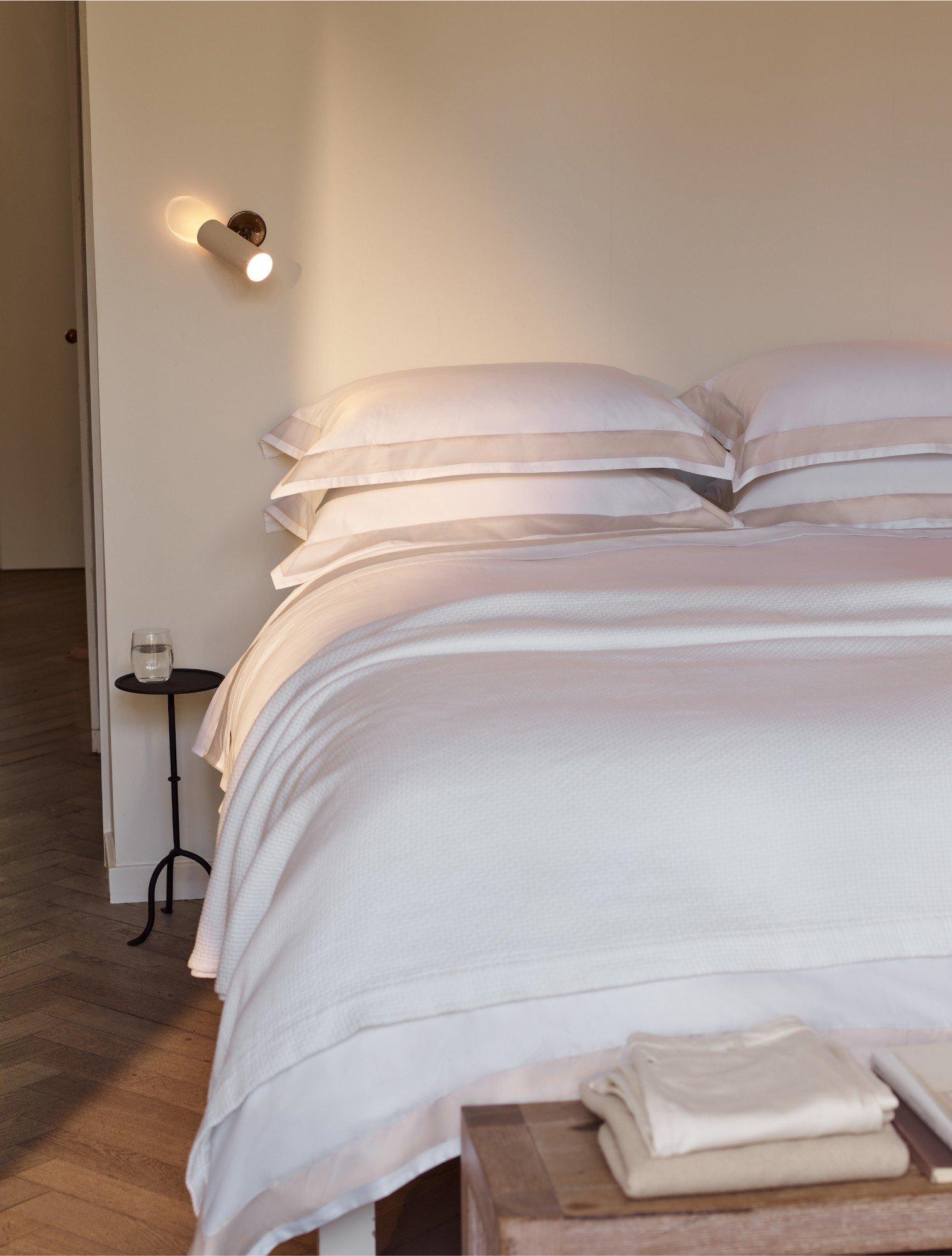 a bed with white sheets and pillows in a bedroom