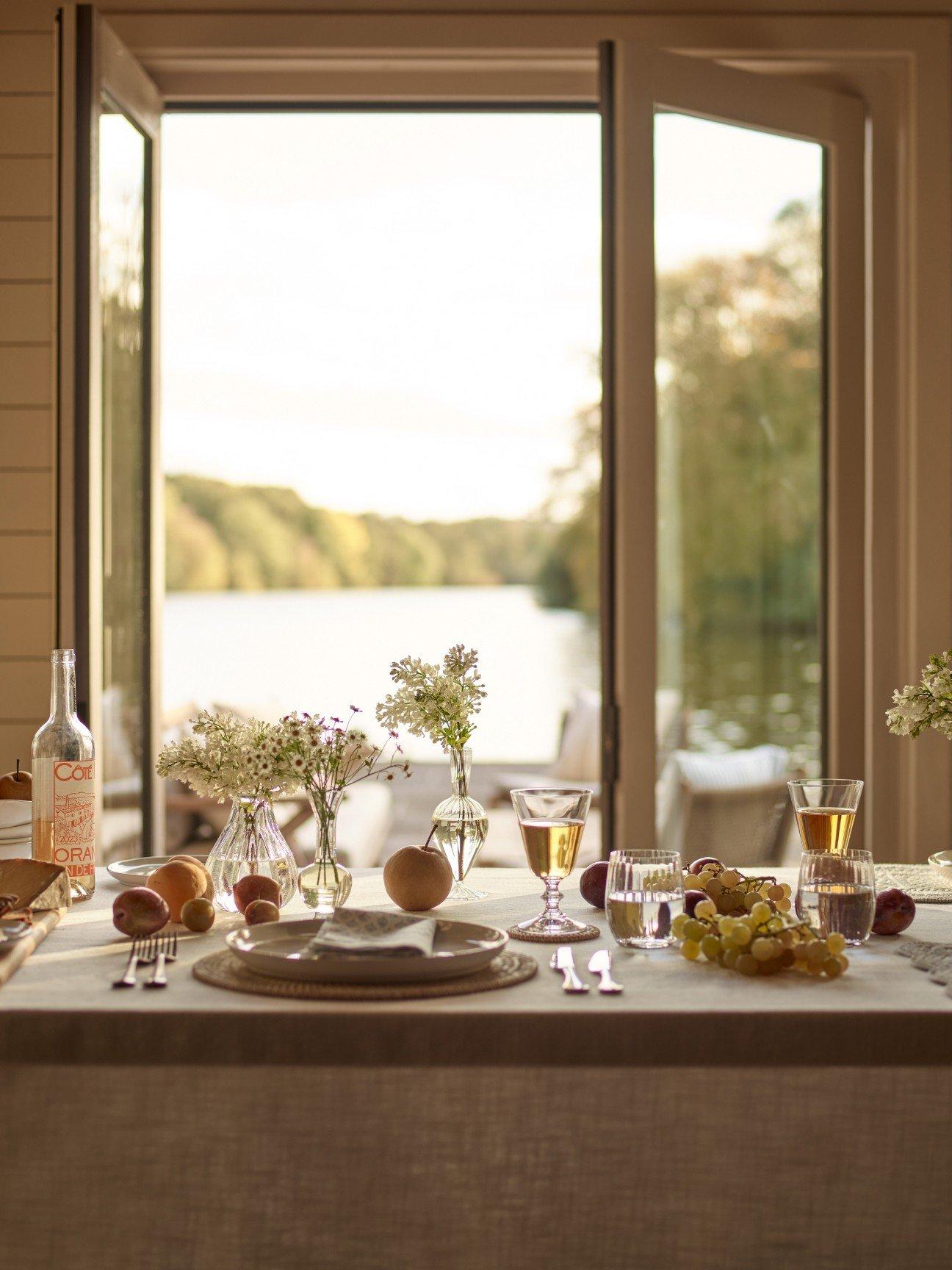 a table set with plates and glasses and flowers on a deck