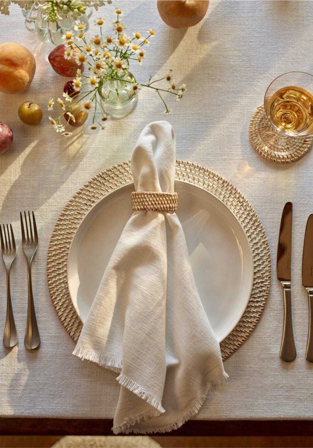 a table setting with a white napkin, silverware, and fruit