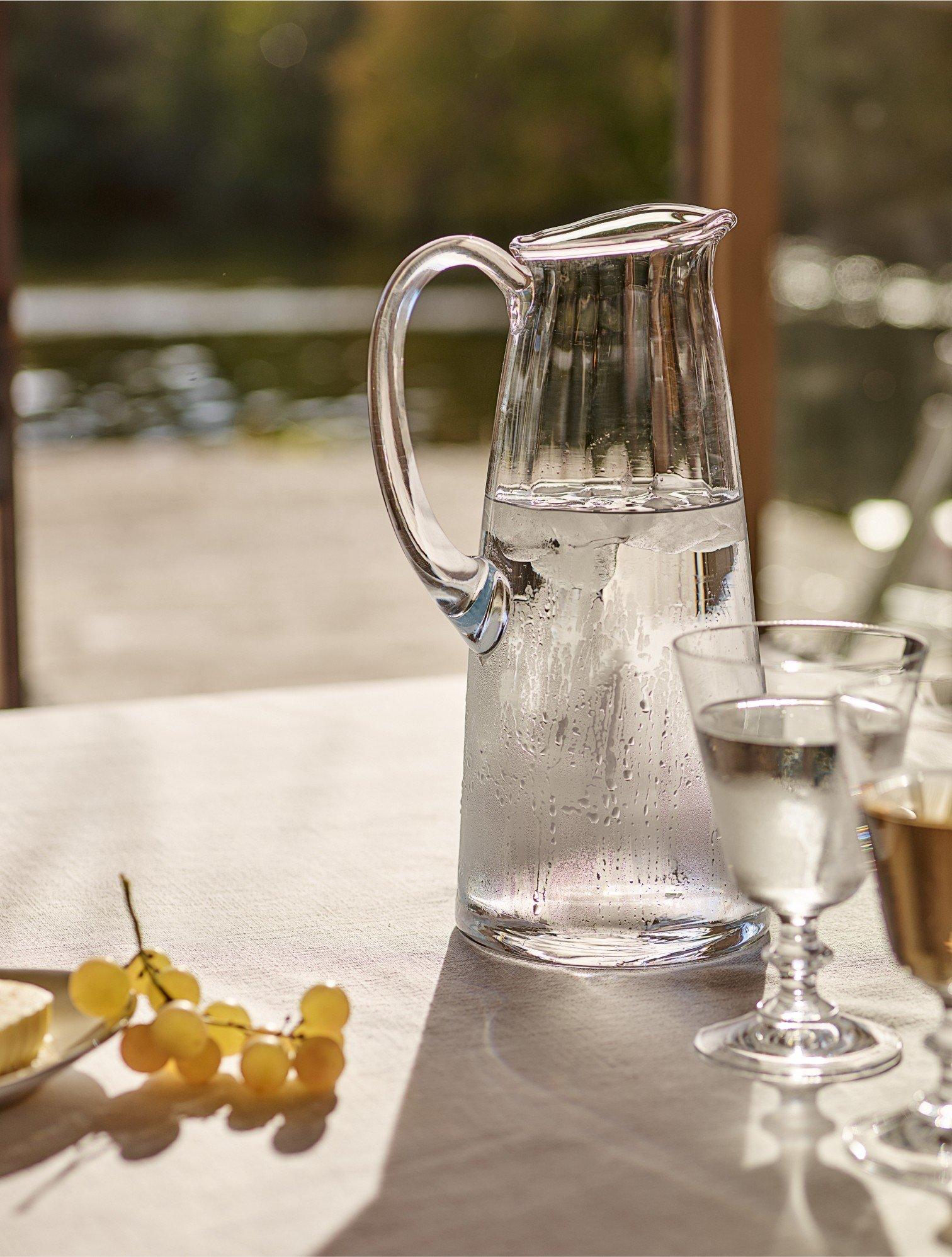 a pitcher of water and two glasses of wine on a table
