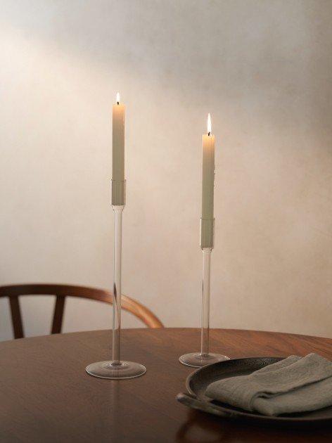 two candles on a table next to a plate and napkin