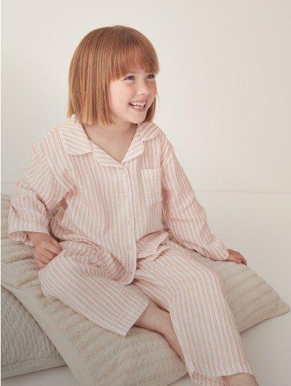 a little girl in pajamas sitting on a pillow on the floor