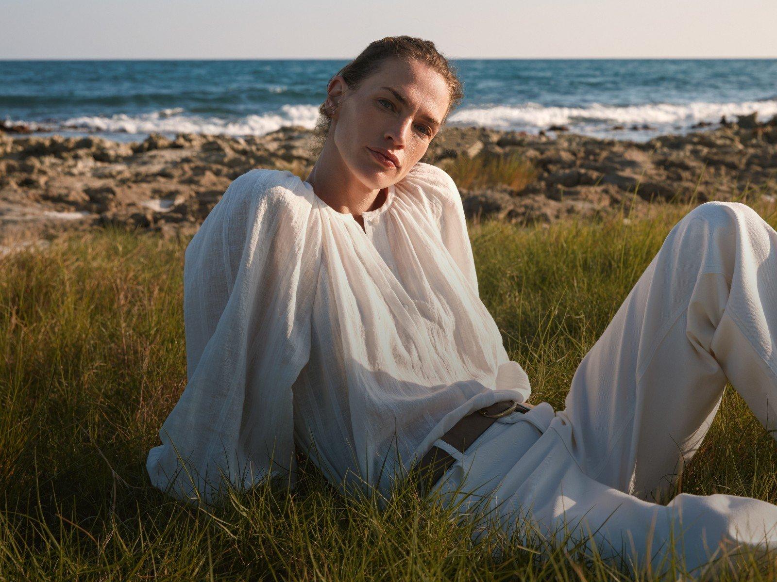 a woman in a white dress walking on the beach