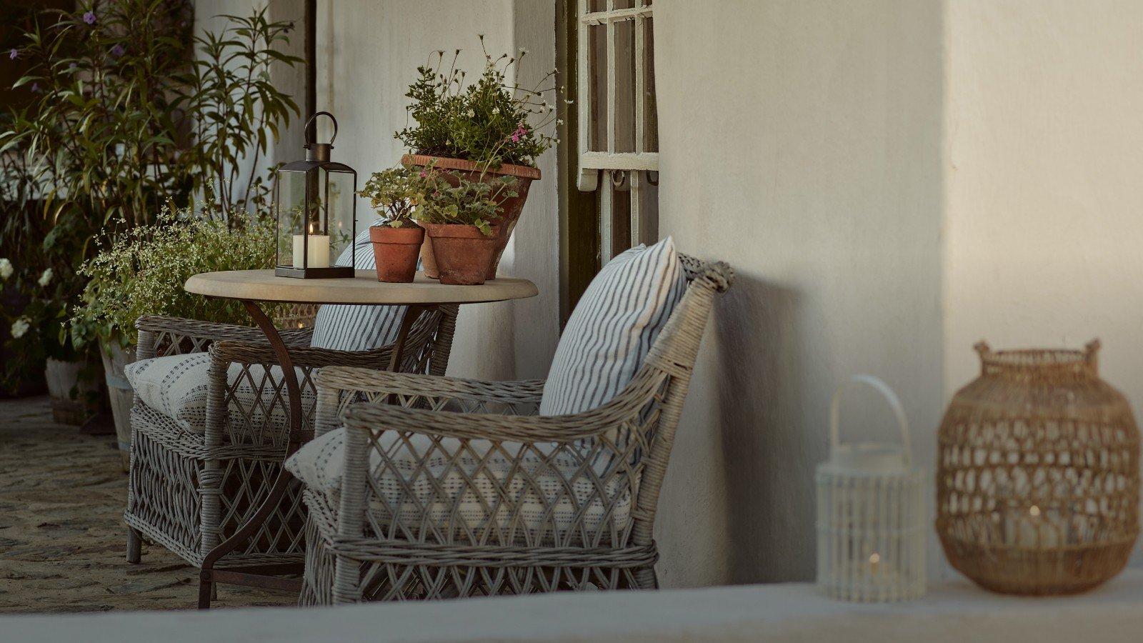 a patio furniture with potted plants on a porch