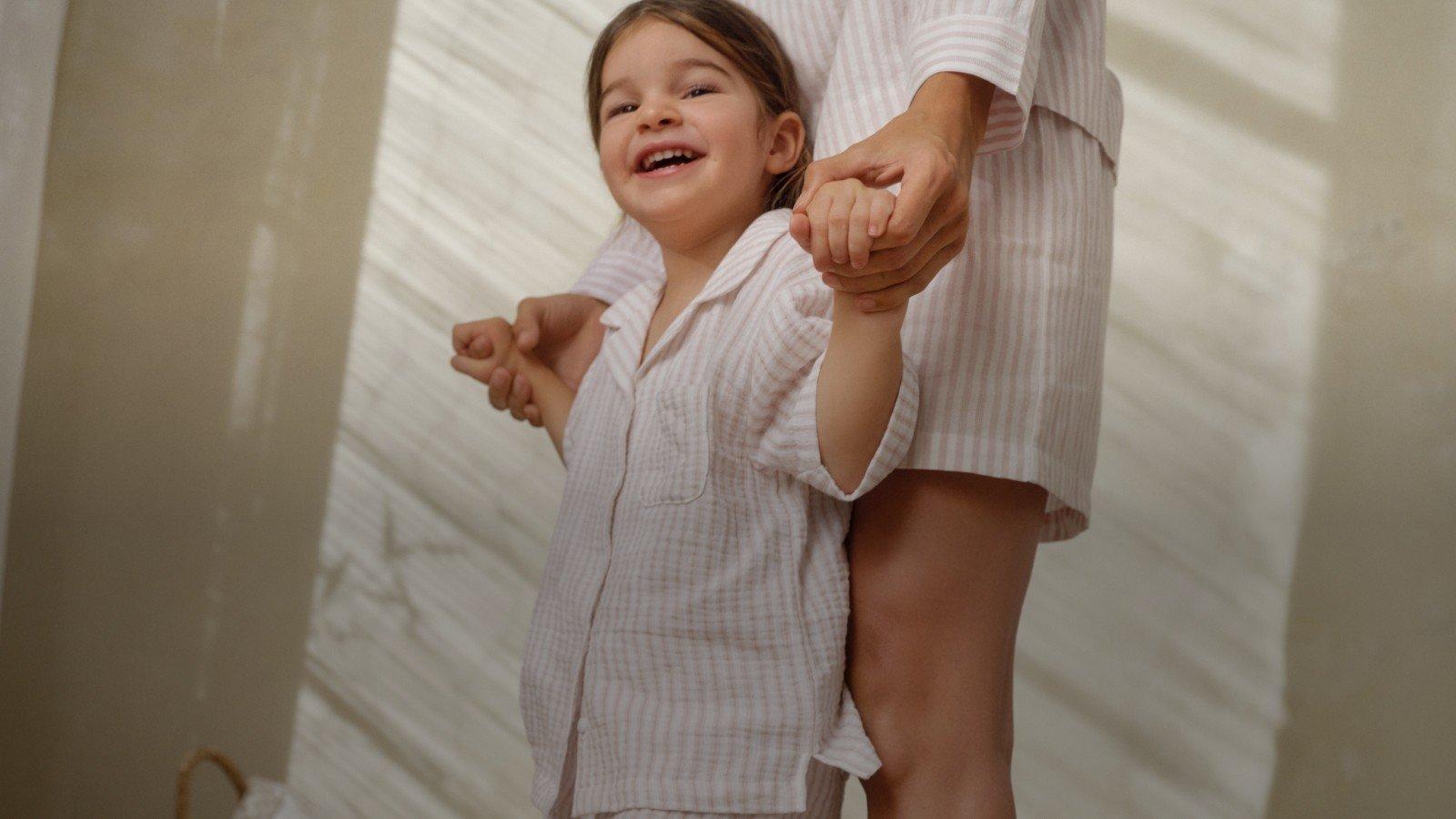 a woman and child standing together in pajamas on a bed