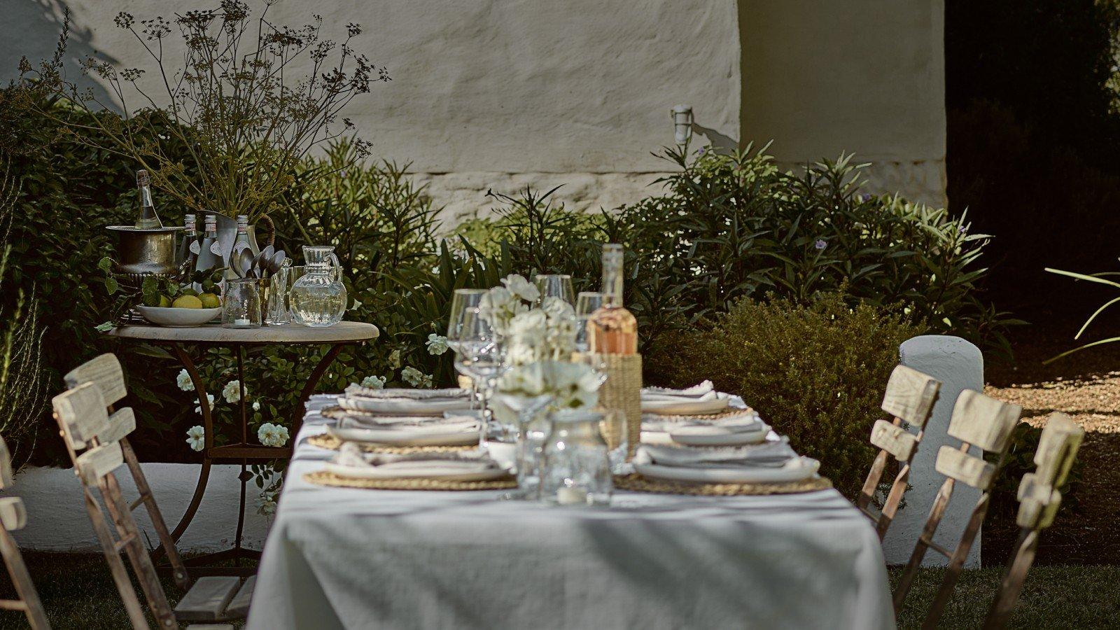 a table set with white table cloth and white plates and glasses