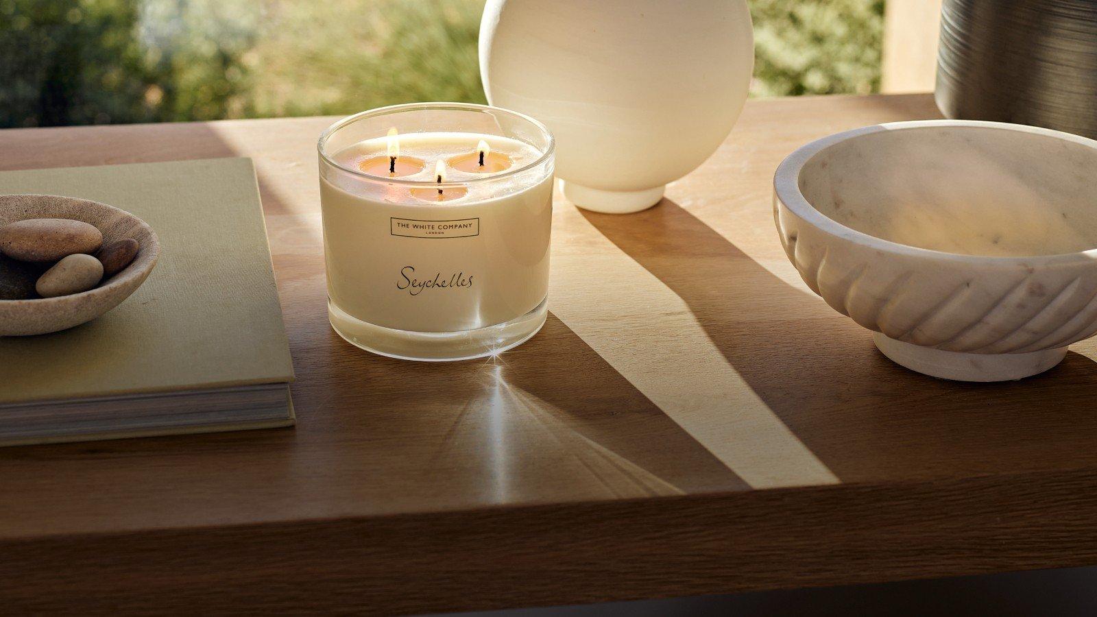 a candle and bowl on a table with a vase of flowers