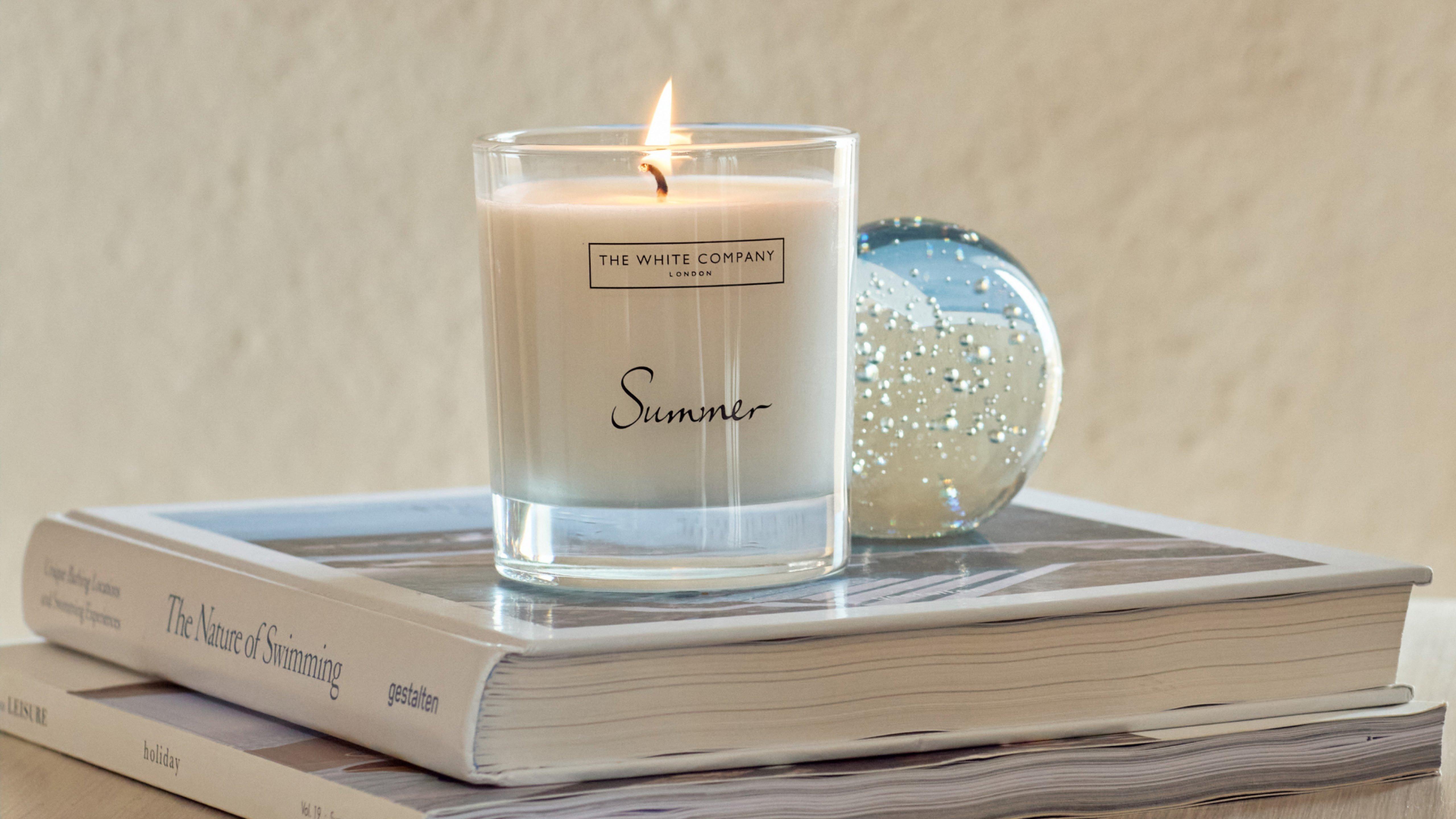 a candle sitting on top of a stack of books with a glass on top of it