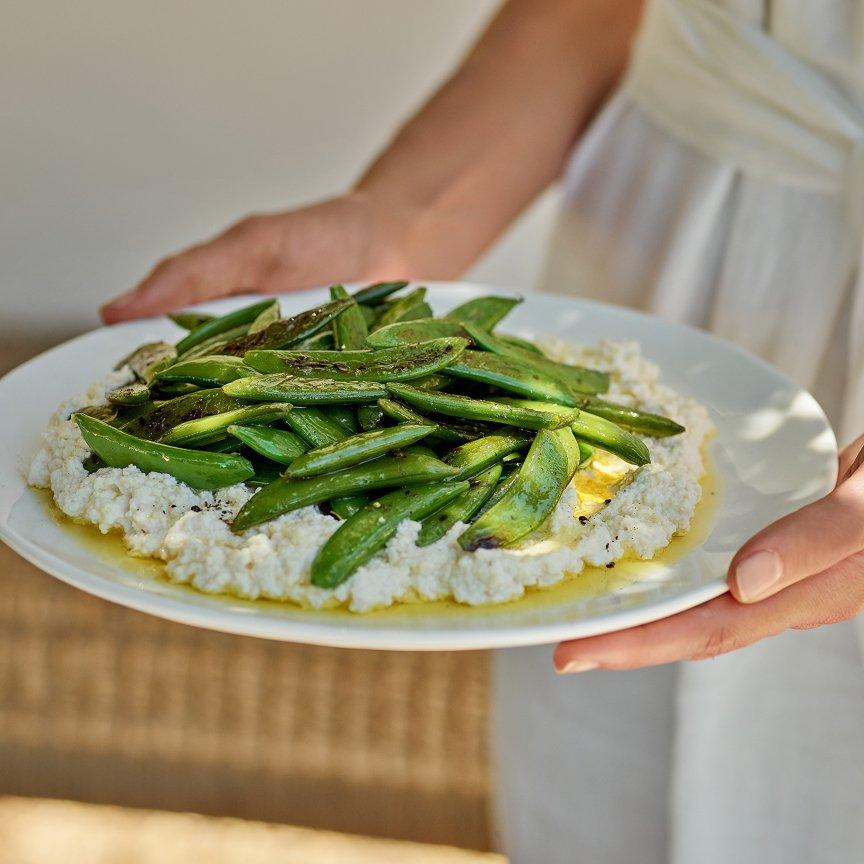 a person holding a plate of food with green beans and rice