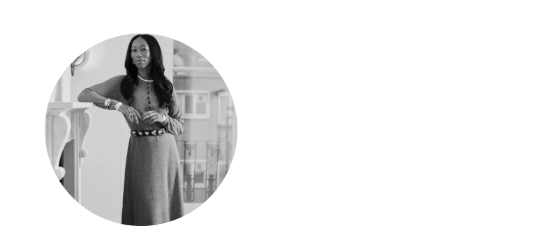 a woman in a dress standing next to a fireplace