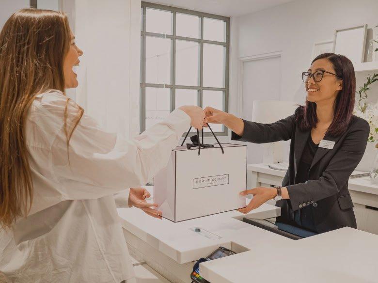a woman handing a bag to another woman at a counter