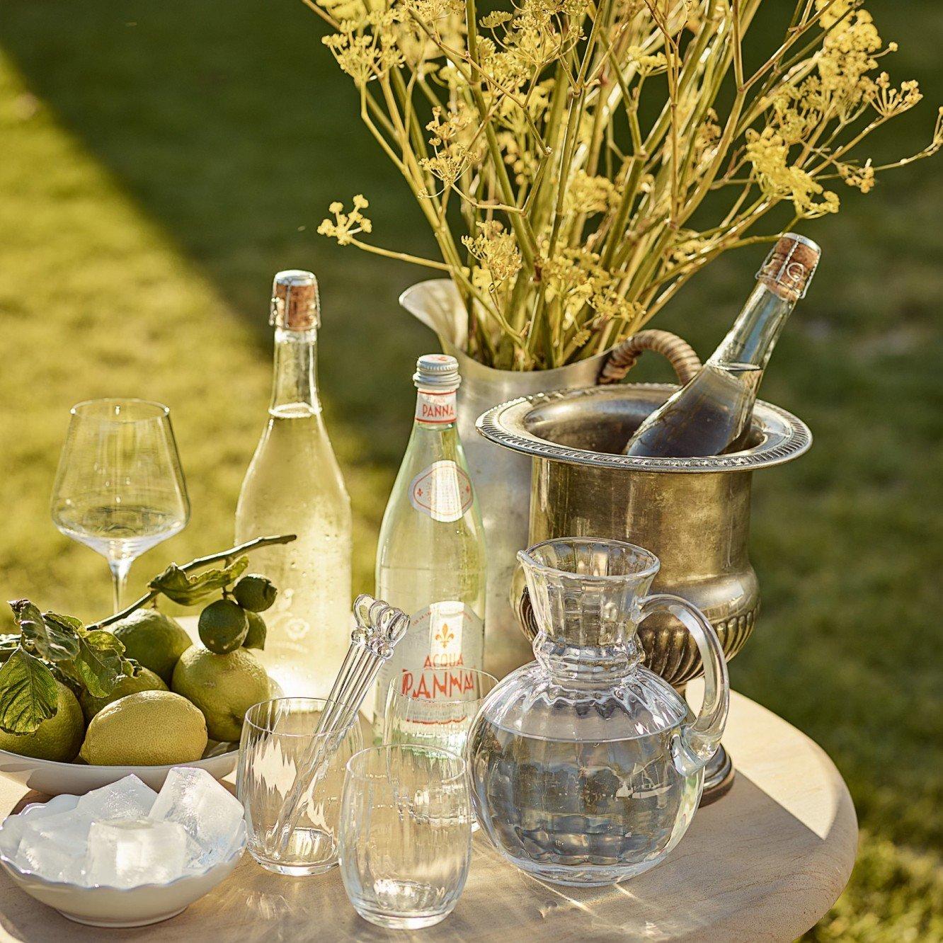 a table with a vase of flowers and bottles of wine