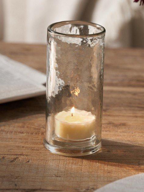 a candle sitting in a glass on a table next to a book