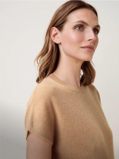 a woman in a tan sweater looking off to the side