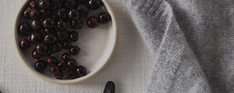 a bowl of cherries on a table next to a curtain