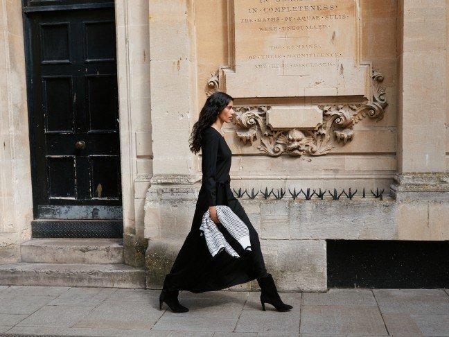 a woman in a long black dress walking down the street