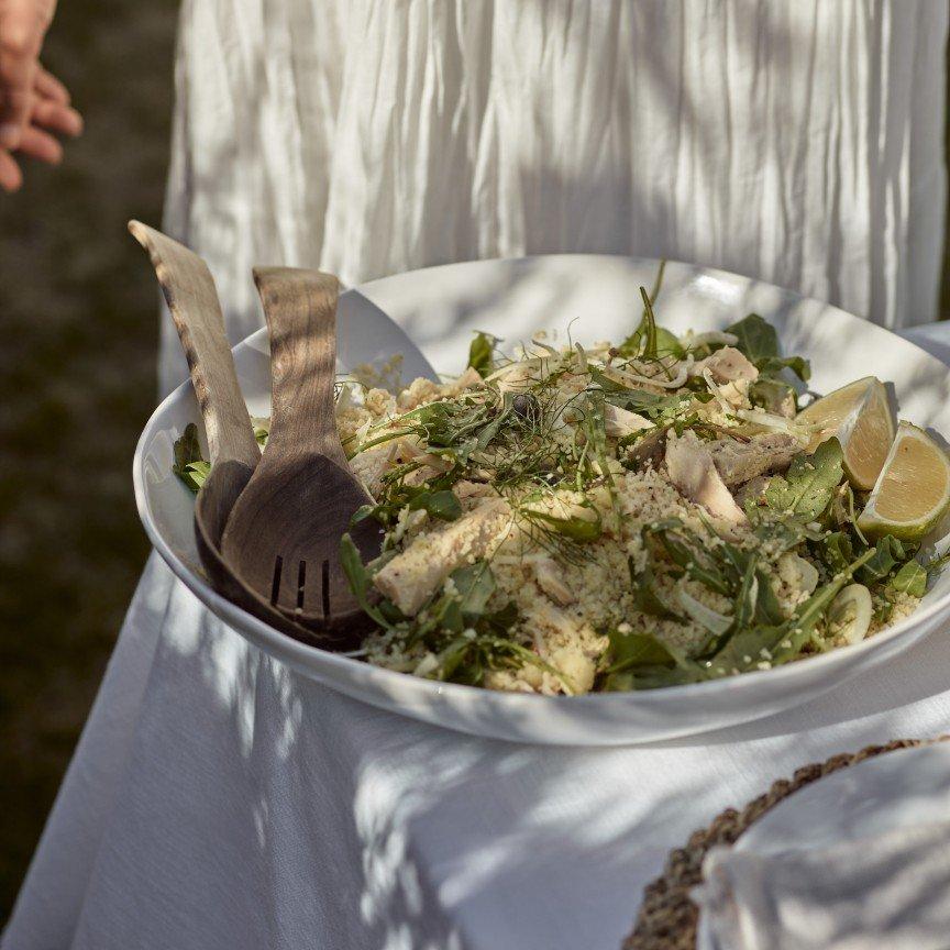 a white plate with a salad and some utensils on a table