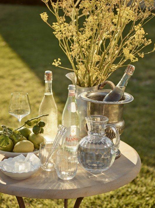 a table with a vase of flowers and bottles of wine