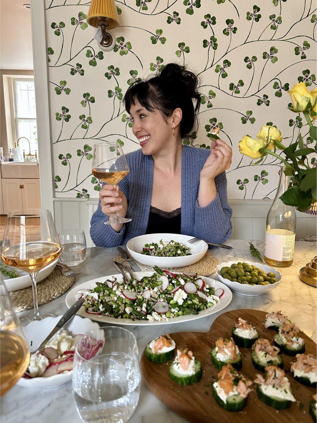a woman holding a plate of food on a table with white table cloth